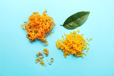 Photo of Flat lay composition with fresh orange zest and leaf on light blue background