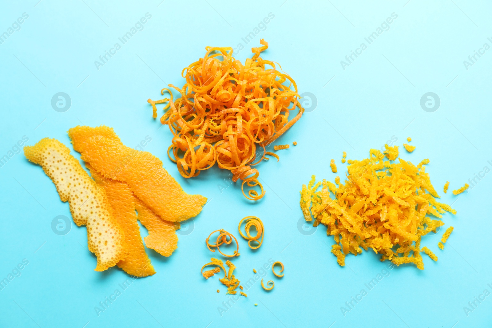 Photo of Flat lay composition with fresh orange zest and peel on light blue background