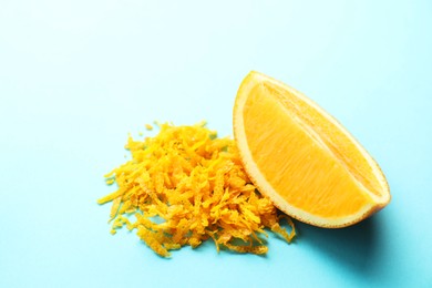 Pile of fresh orange zest and cut fruit on light blue background, closeup