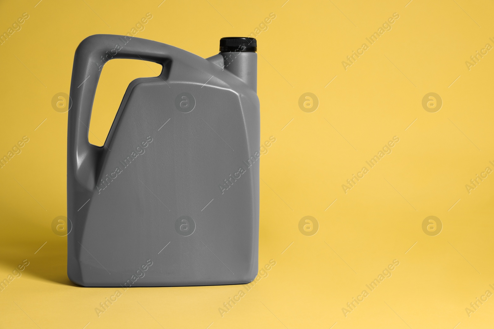 Photo of One grey plastic canister on yellow background, space for text