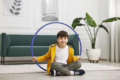 Boy with hula hoop on floor at home