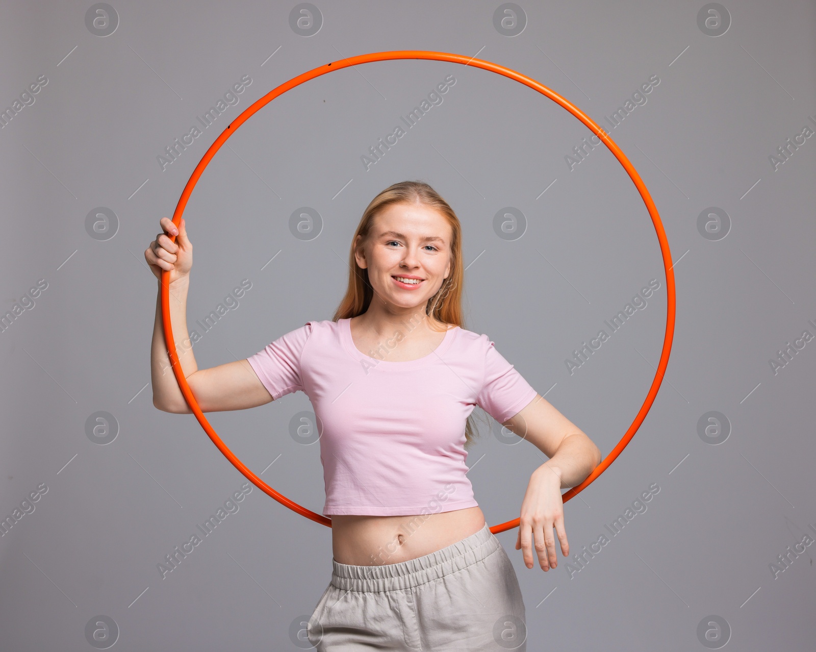 Photo of Beautiful young woman with hula hoop on grey background