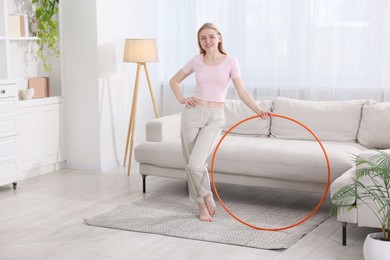 Beautiful young woman with hula hoop at home