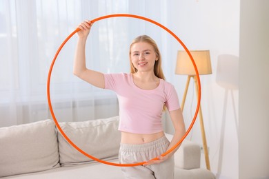 Beautiful young woman with hula hoop at home