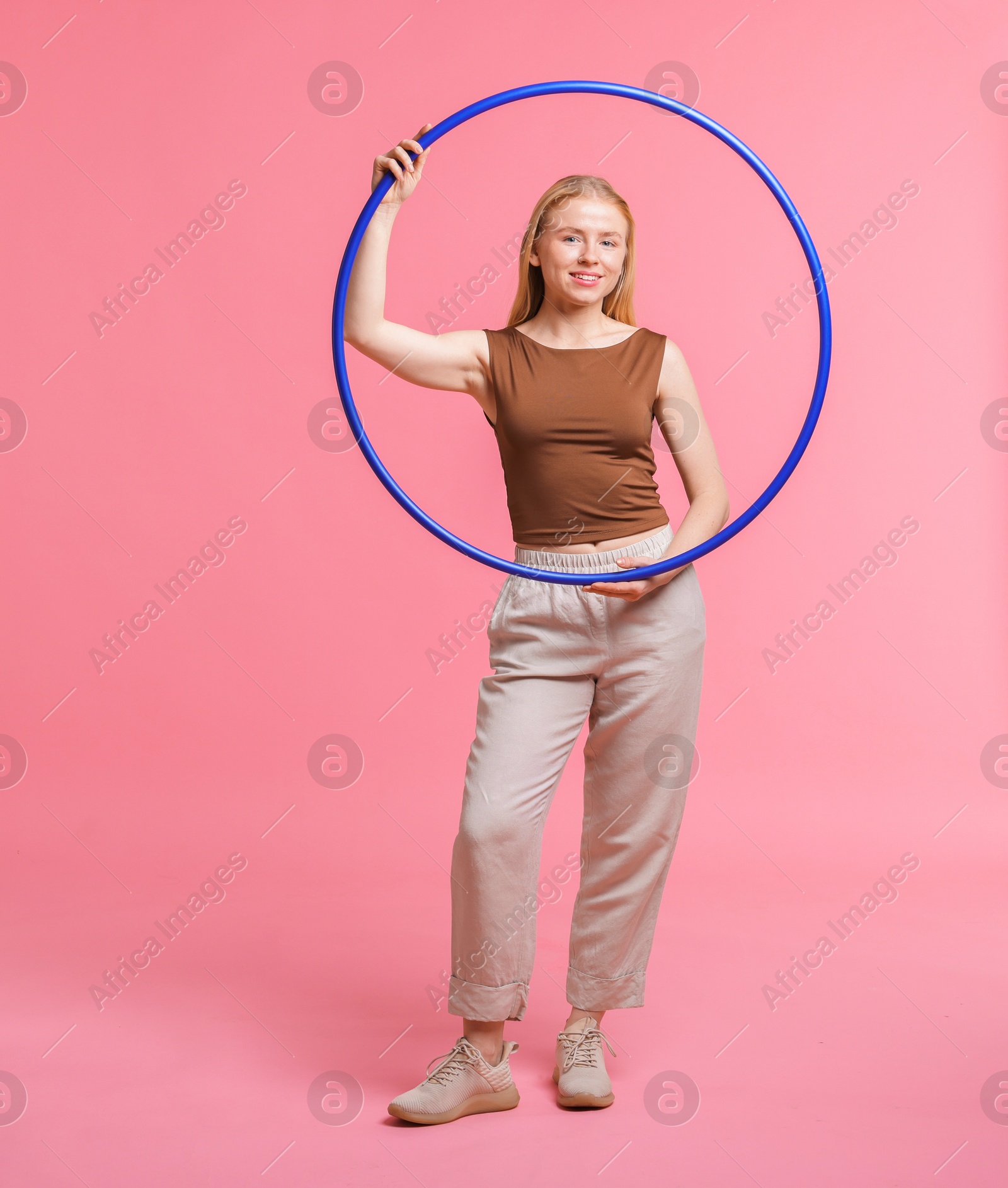 Photo of Beautiful young woman with hula hoop on pink background