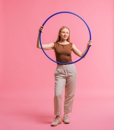 Beautiful young woman with hula hoop on pink background, space for text