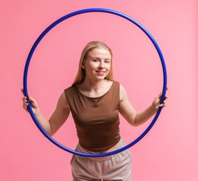 Photo of Beautiful young woman with hula hoop on pink background, space for text