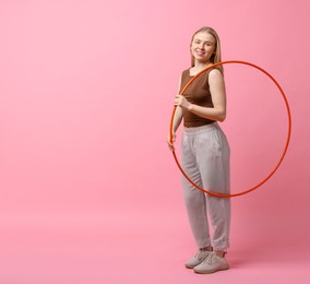 Beautiful young woman with hula hoop on pink background, space for text