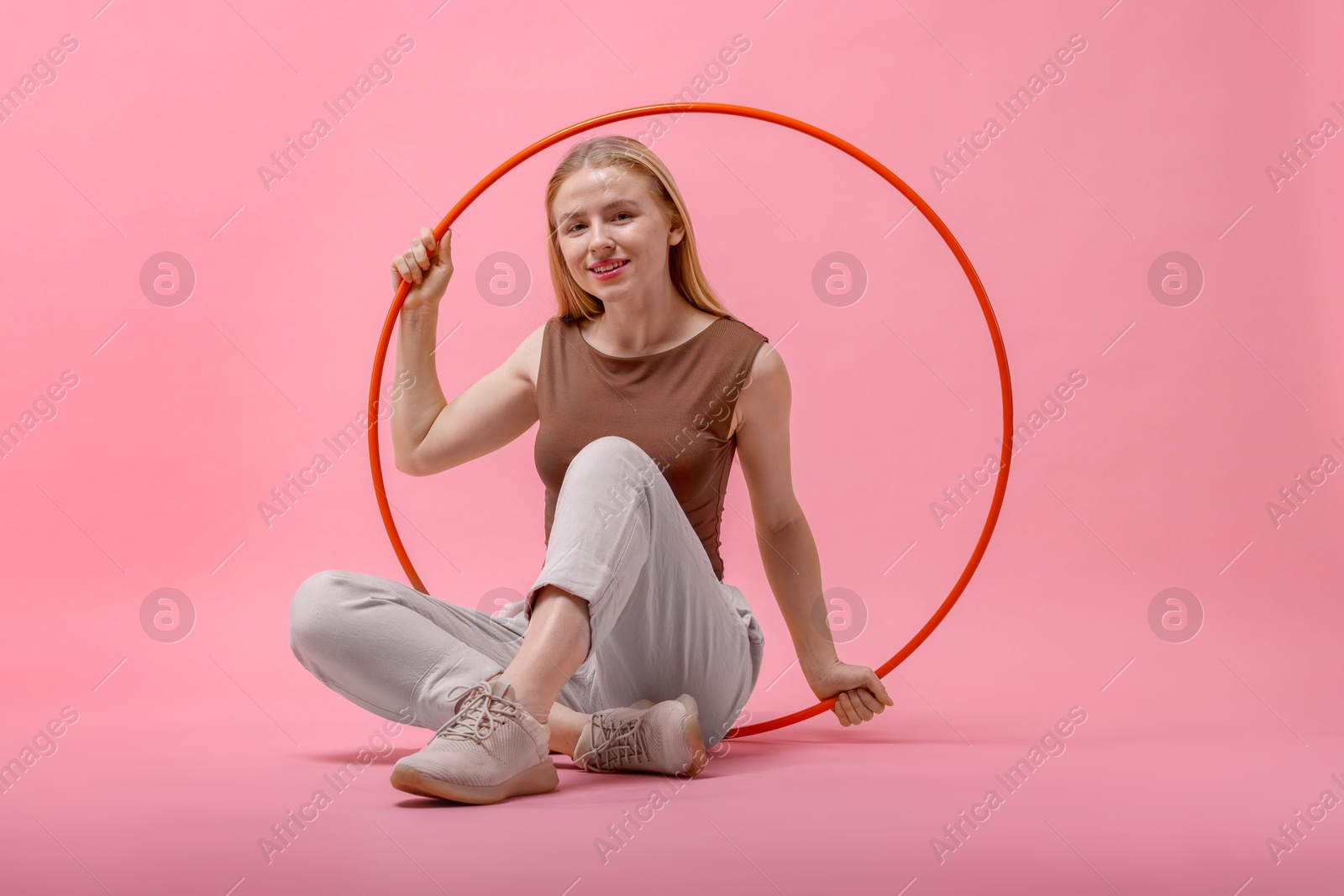 Photo of Beautiful young woman with hula hoop on pink background