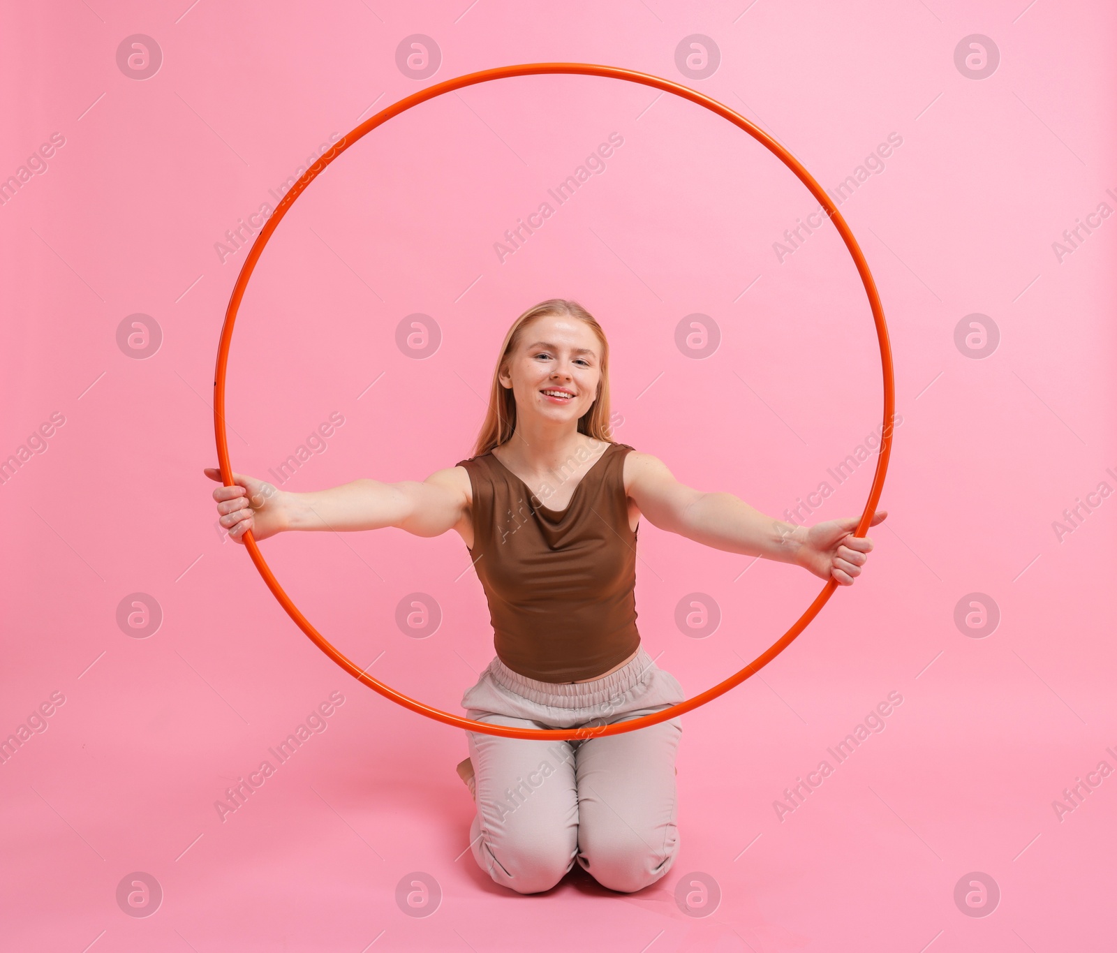 Photo of Beautiful young woman with hula hoop on pink background