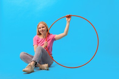 Photo of Beautiful young woman with hula hoop on light blue background