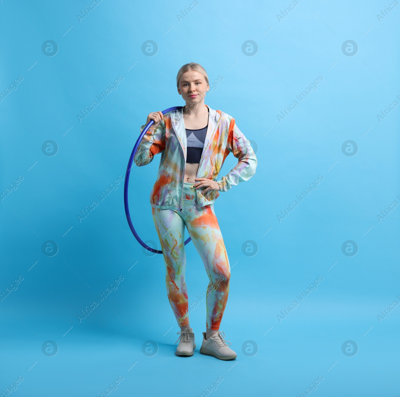 Photo of Beautiful young woman with hula hoop on light blue background