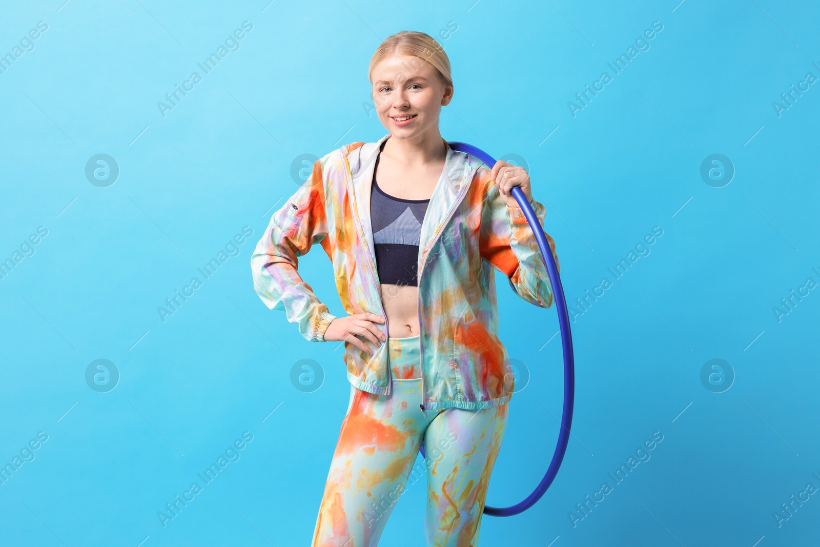 Photo of Beautiful young woman with hula hoop on light blue background