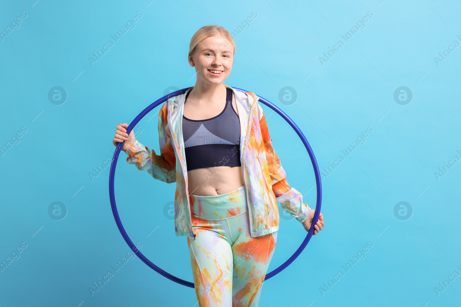 Photo of Beautiful young woman with hula hoop on light blue background