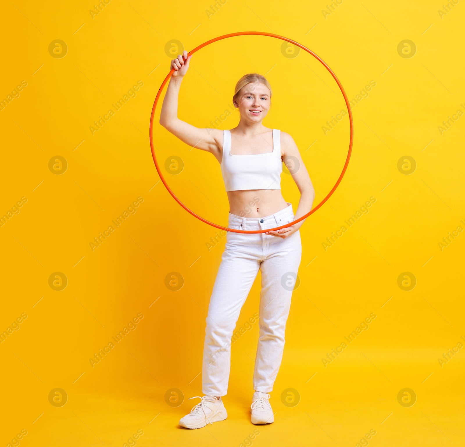 Photo of Beautiful young woman with hula hoop on yellow background