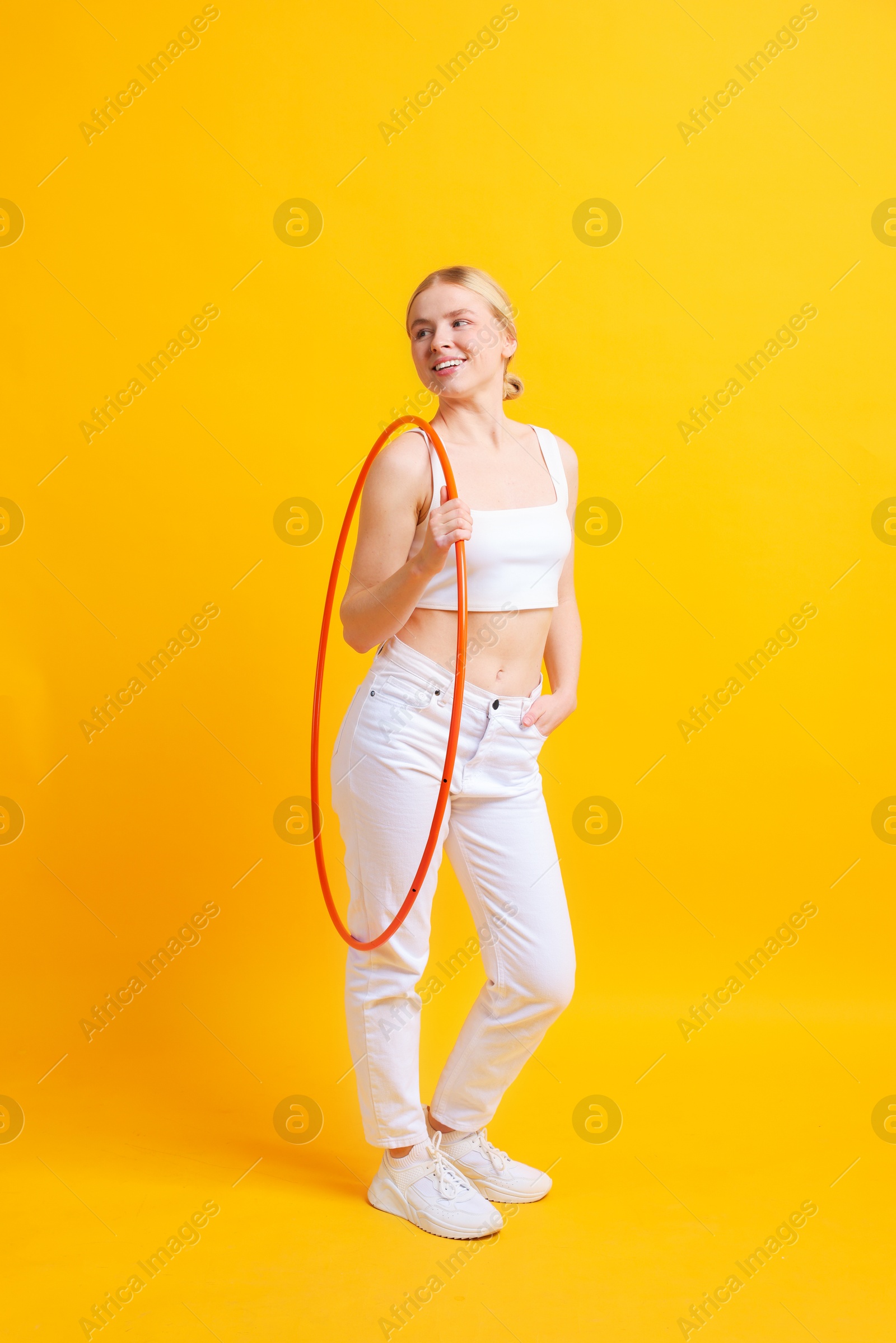 Photo of Beautiful young woman with hula hoop on yellow background