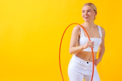 Beautiful young woman with hula hoop on yellow background, space for text