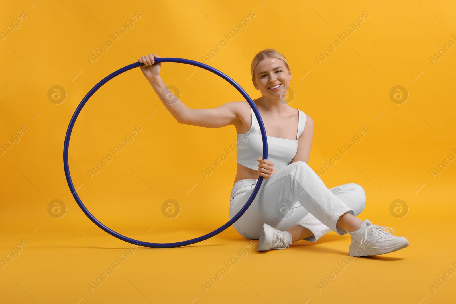 Photo of Beautiful young woman with hula hoop on yellow background