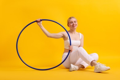 Photo of Beautiful young woman with hula hoop on yellow background