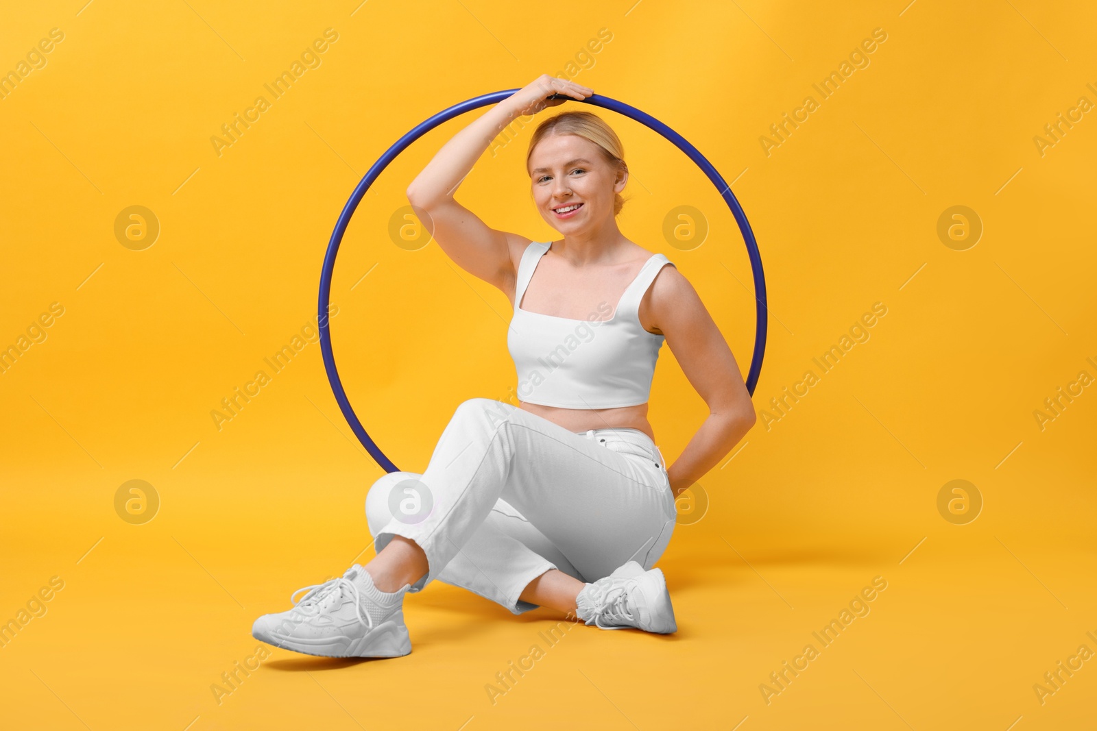 Photo of Beautiful young woman with hula hoop on yellow background