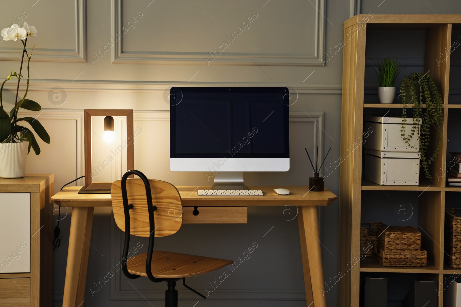 Comfortable workplace with modern computer and lamp on wooden desk in home office Photo of Comfortable workplace with modern computer and lamp on wooden desk in home office