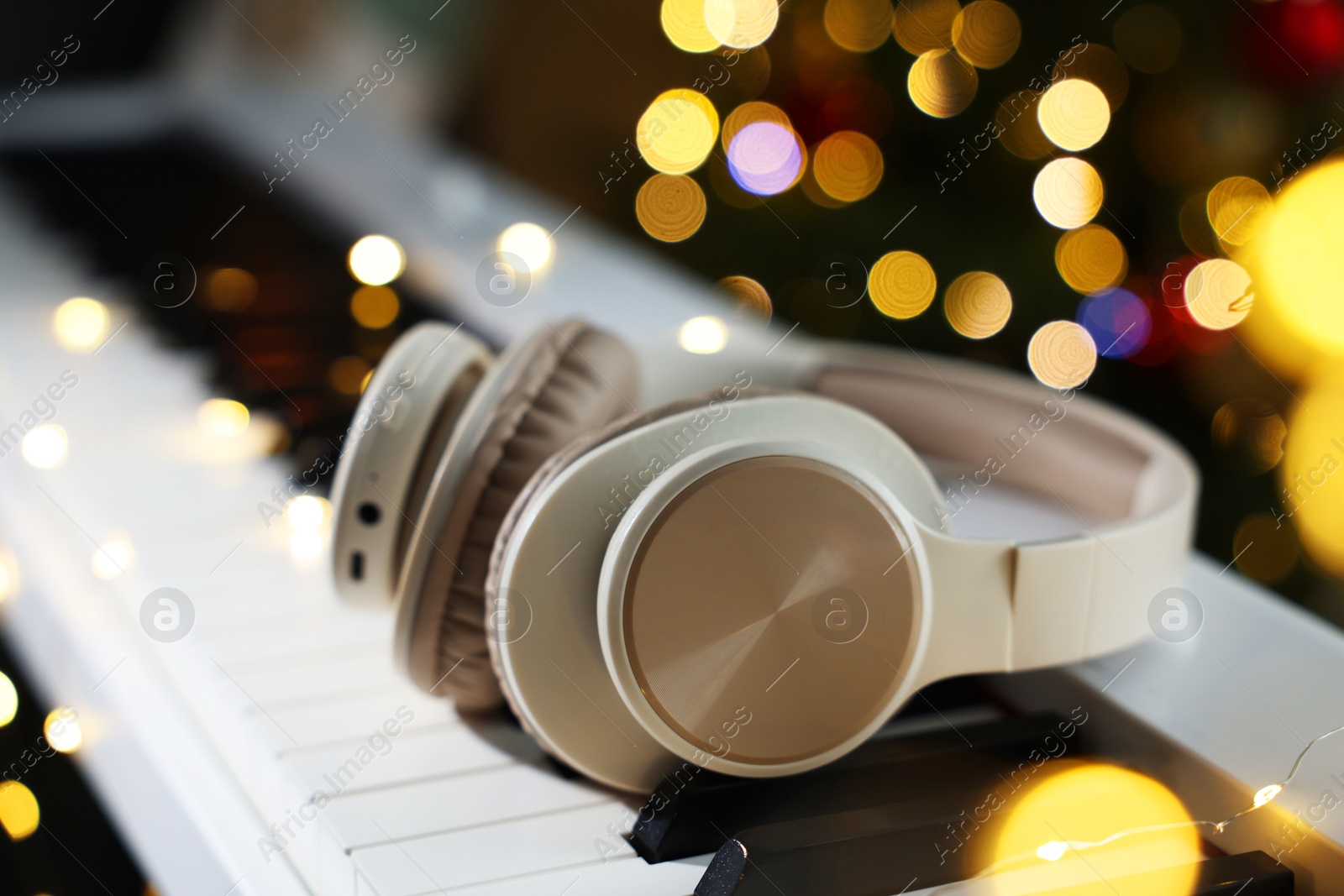 Headphones on electric piano against blurred lights, closeup. Bokeh effect Photo of Headphones on electric piano against blurred lights, closeup. Bokeh effect