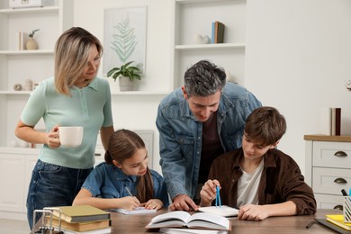 Parents helping their children with homework at table indoors