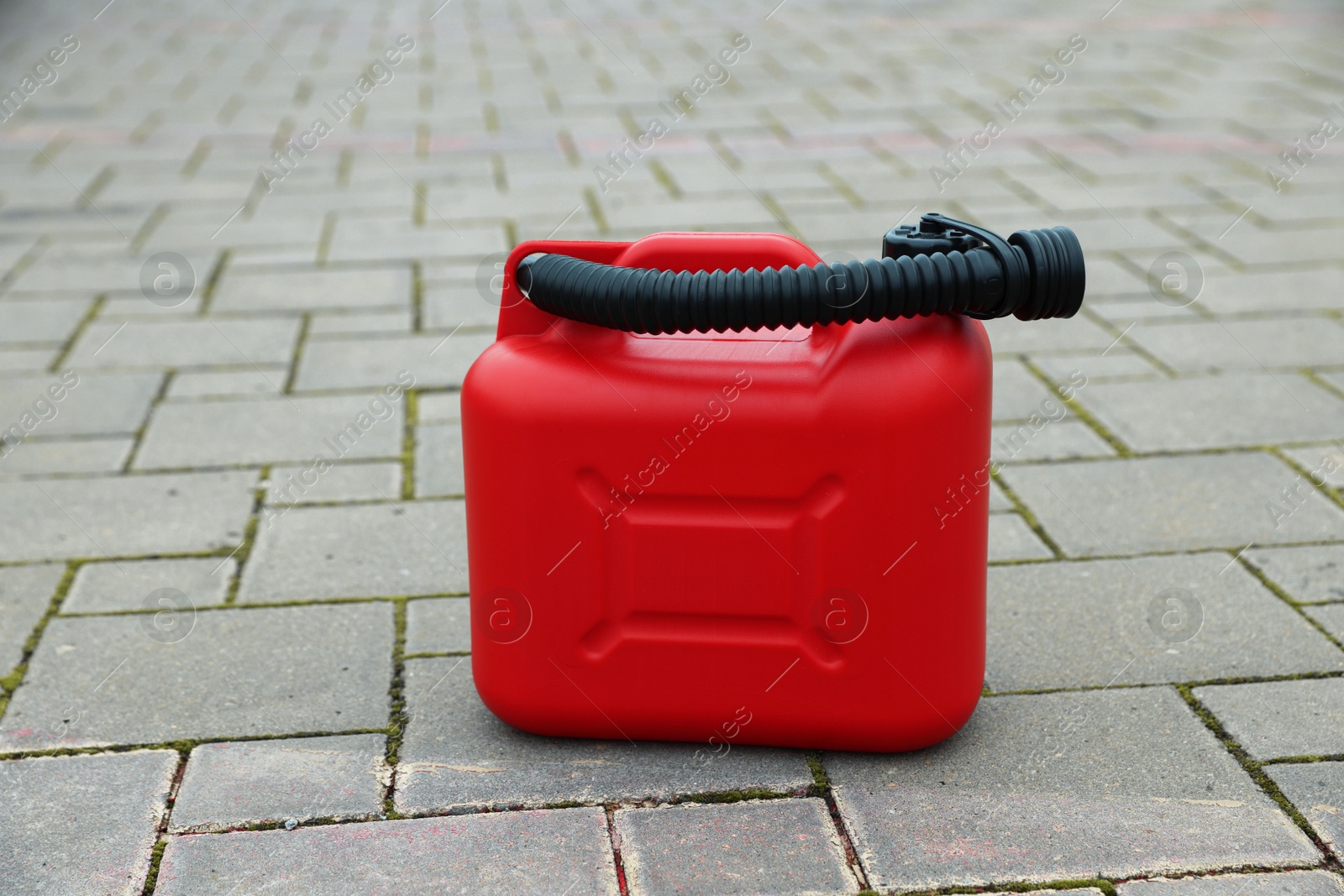 Photo of One red plastic canister with spout outdoors