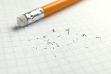 Photo of Pencil with eraser and scraps on white sheet of paper, selective focus