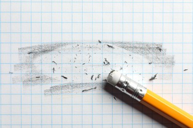 Photo of Pencil with eraser and scraps on white sheet of paper, top view