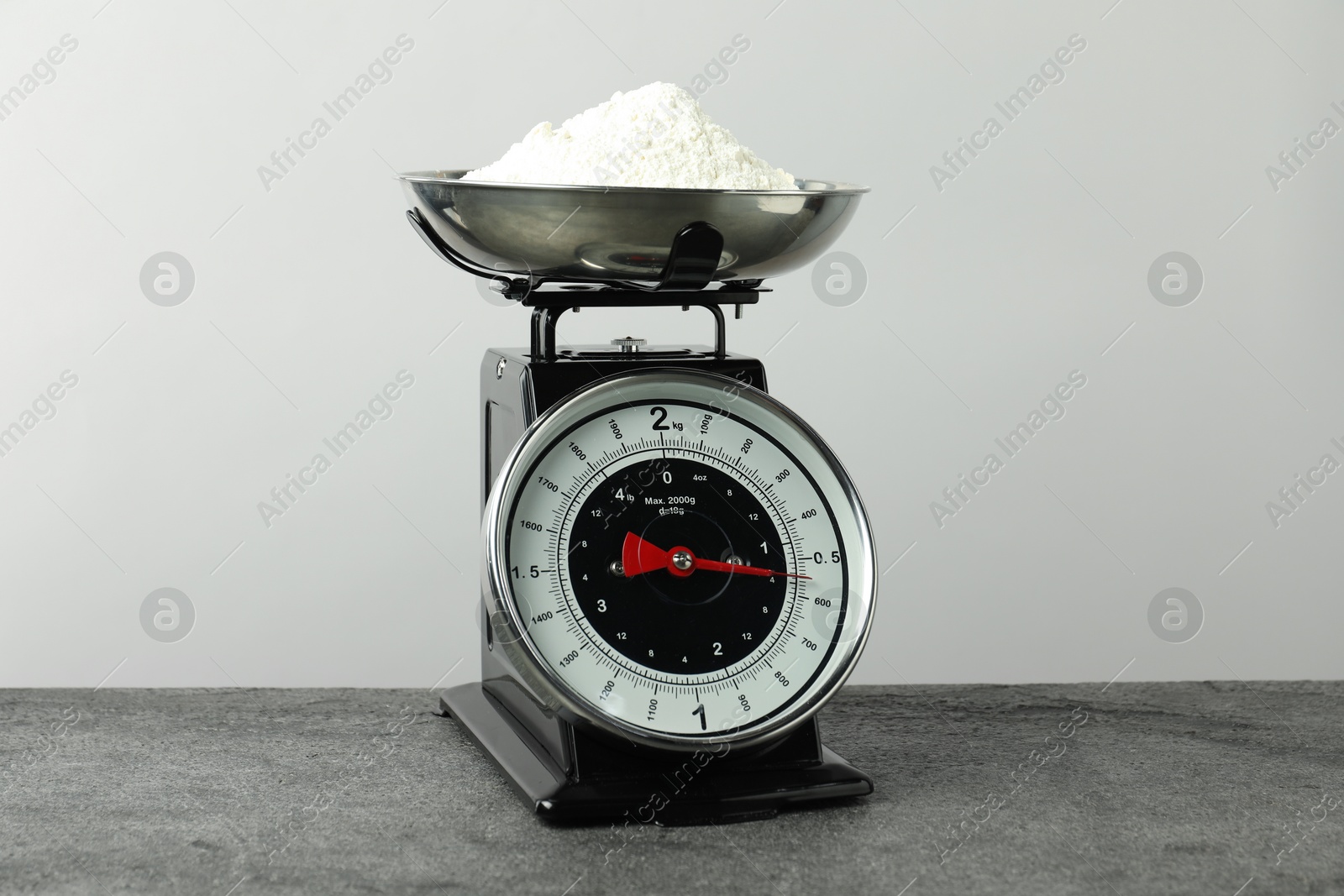 Photo of Retro mechanical kitchen scale with flour on grey table