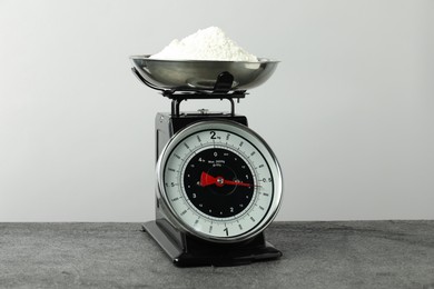 Retro mechanical kitchen scale with flour on grey table