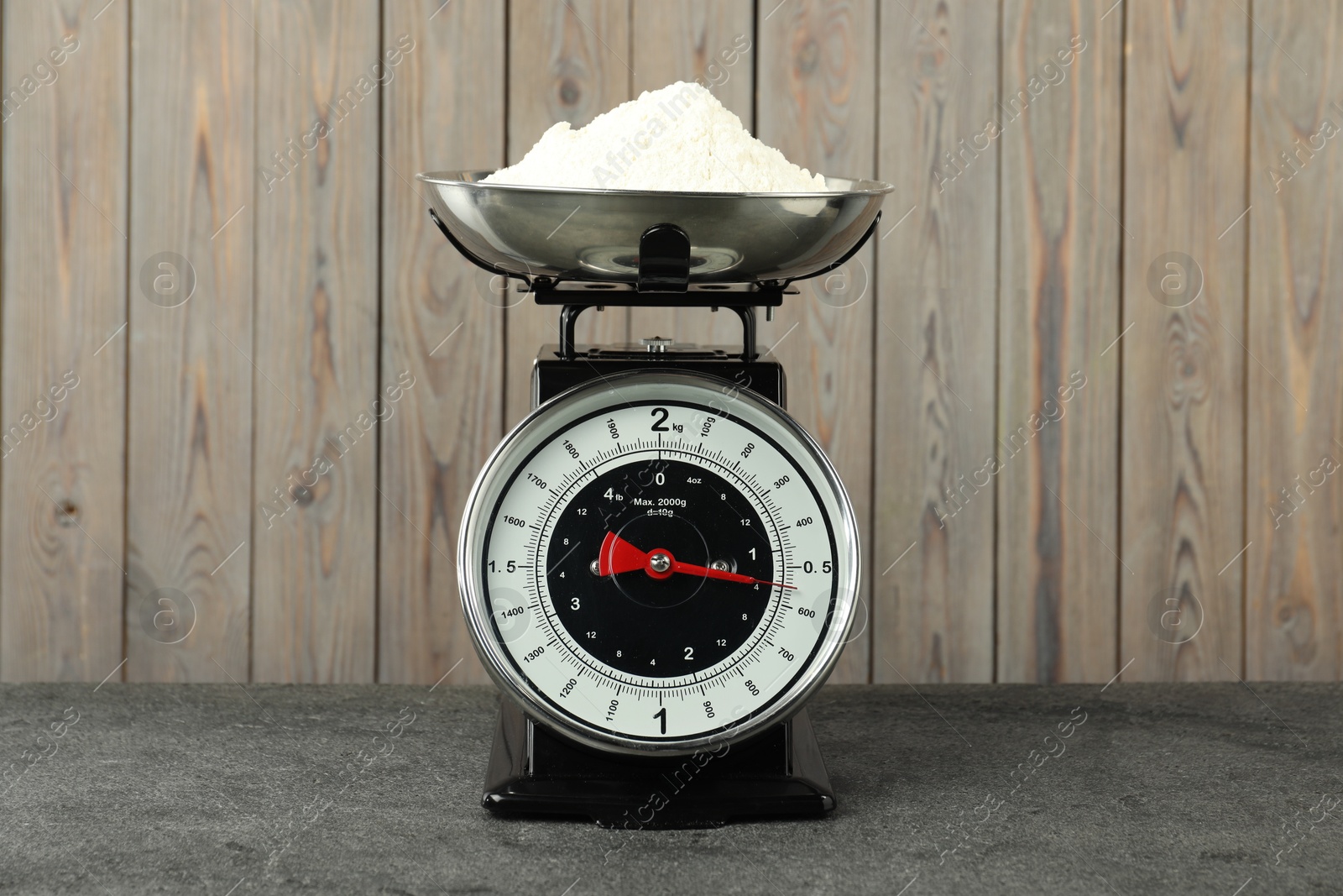 Photo of Retro mechanical kitchen scale with flour on grey table