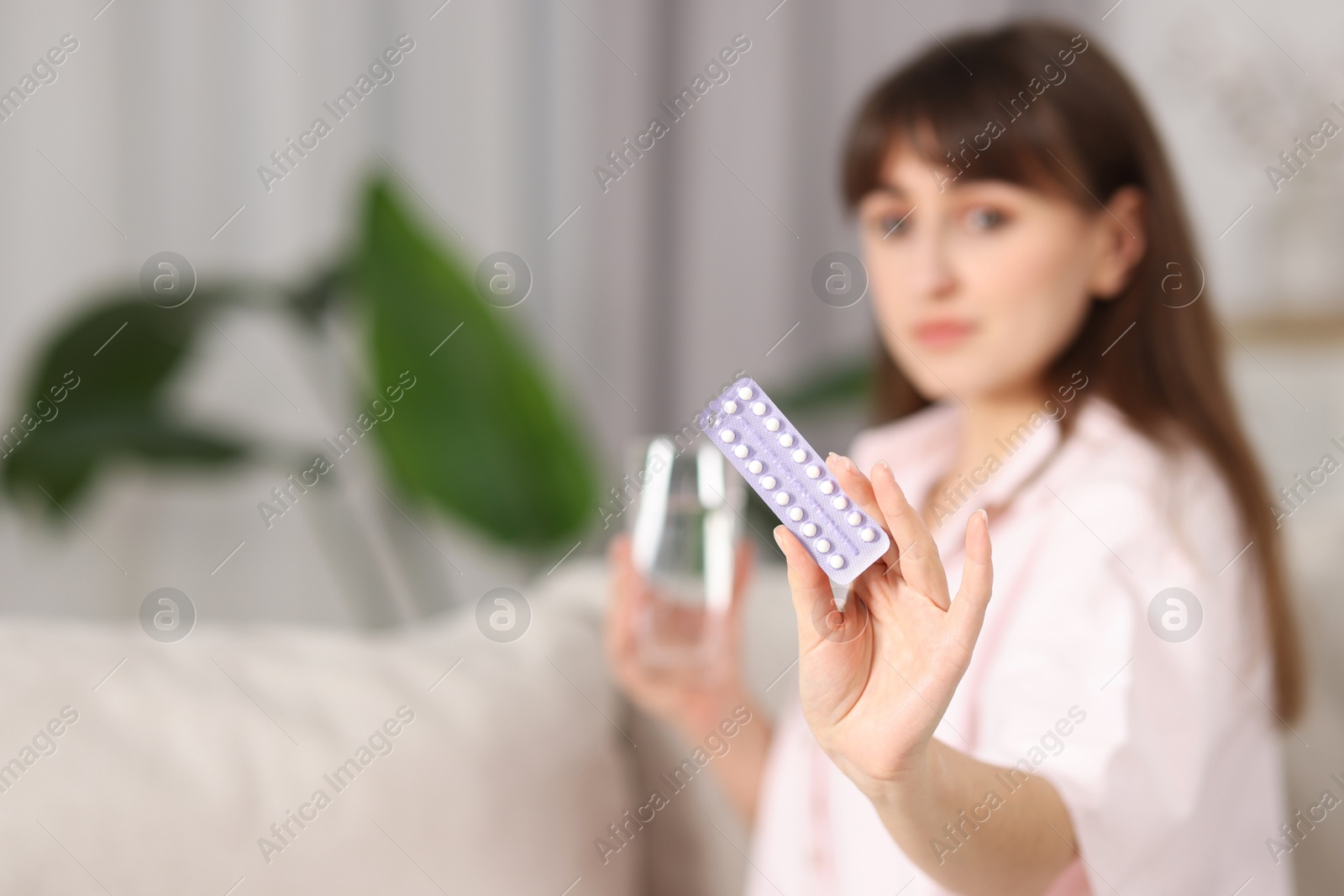 Photo of Woman with blister of contraceptive pills indoors, selective focus. Space for text