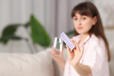 Woman with blister of contraceptive pills indoors, selective focus. Space for text