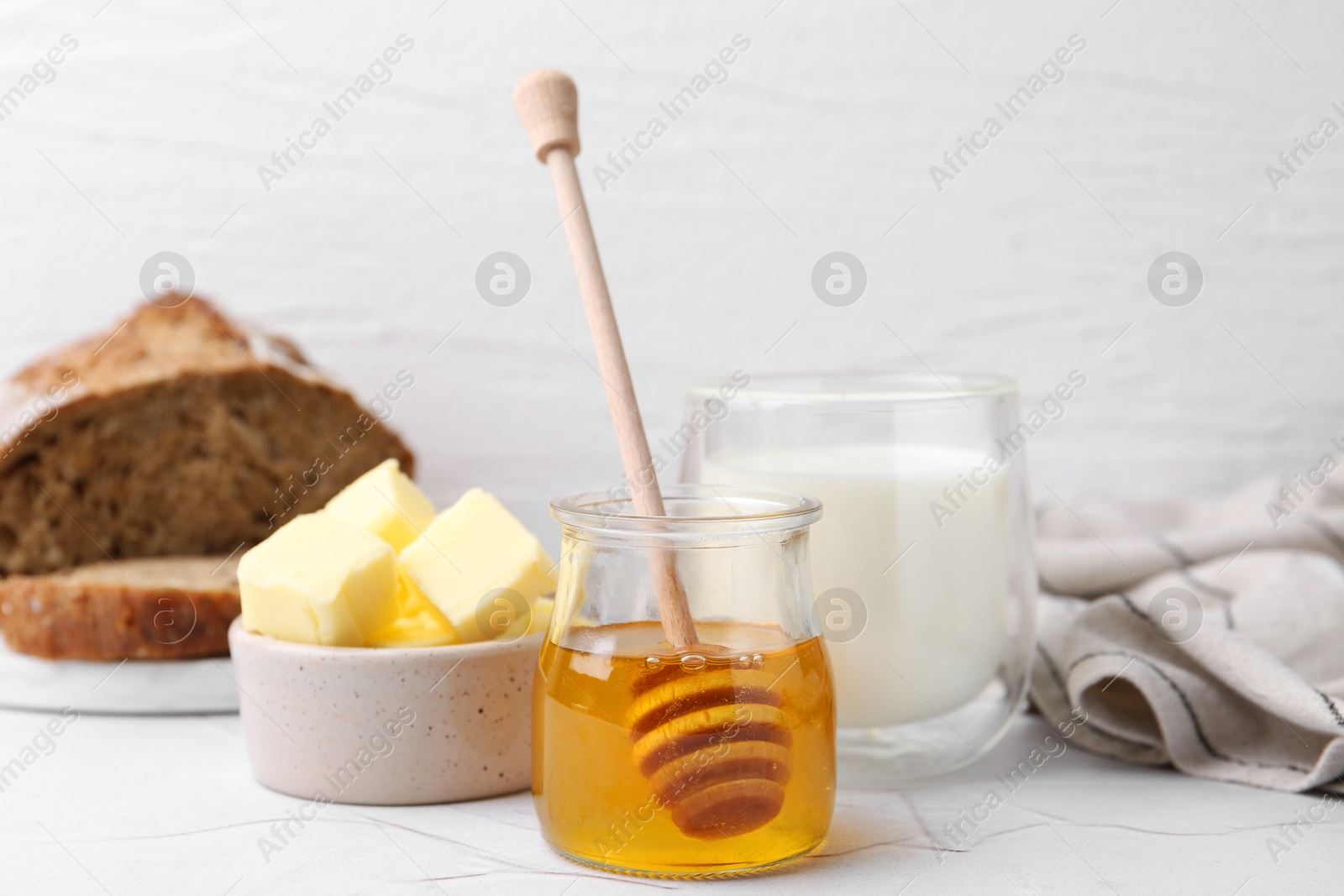 Photo of Sweet honey, butter and milk on white table