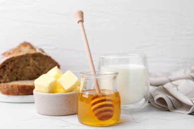 Photo of Sweet honey, butter and milk on white table