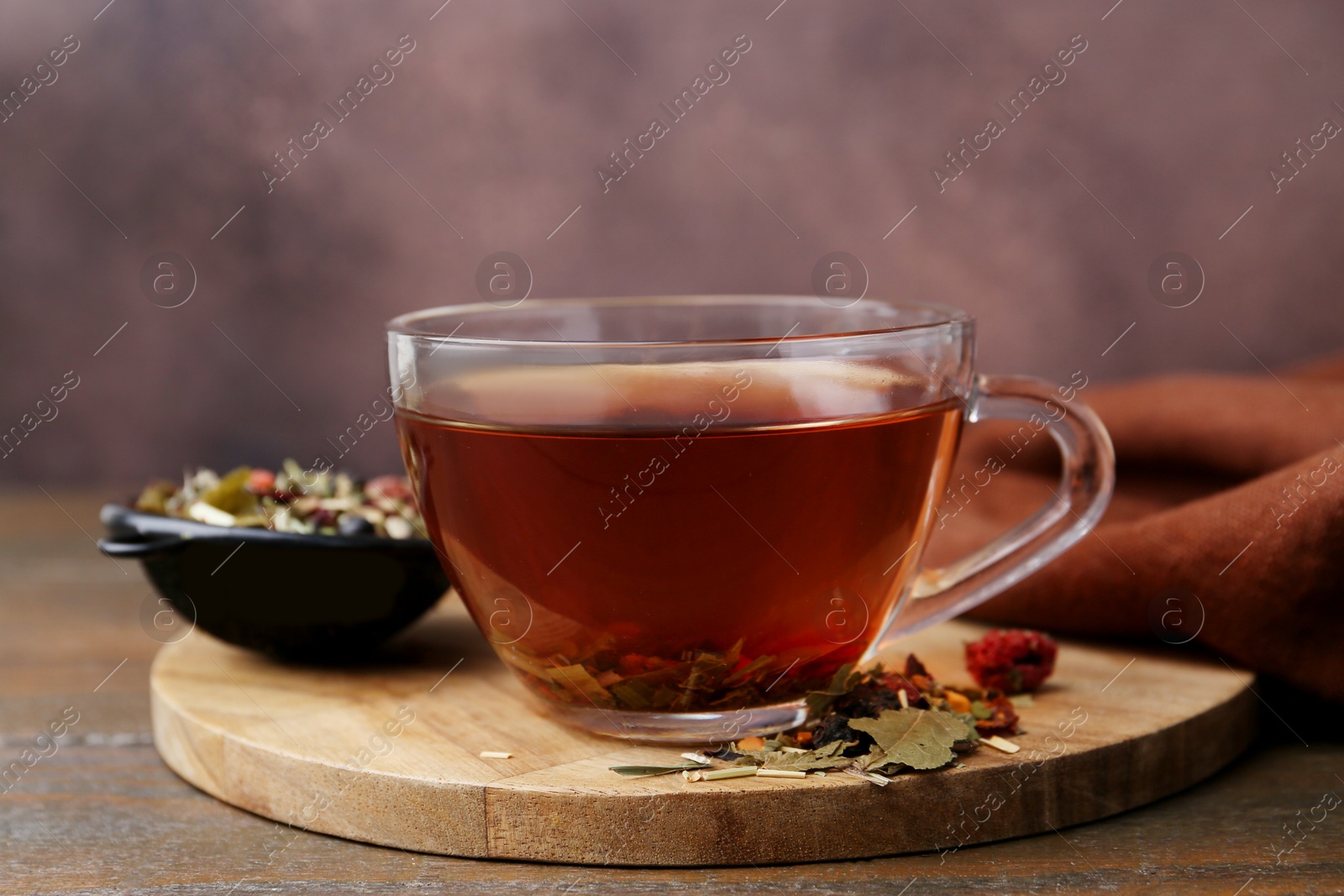 Delicious herbal tea and dry leaves on wooden table, closeup Photo of Delicious herbal tea and dry leaves on wooden table, closeup