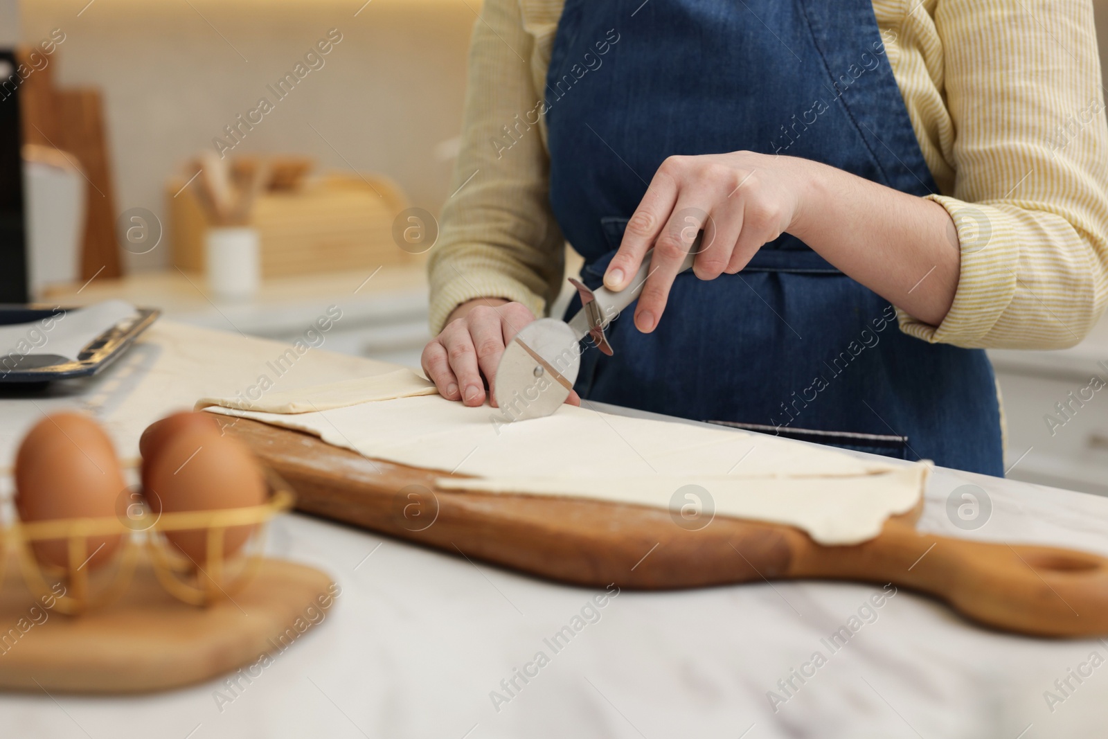 Woman cutting dough at light marble table indoors, closeup. Making croissants Photo of Woman cutting dough at light marble table indoors, closeup. Making croissants