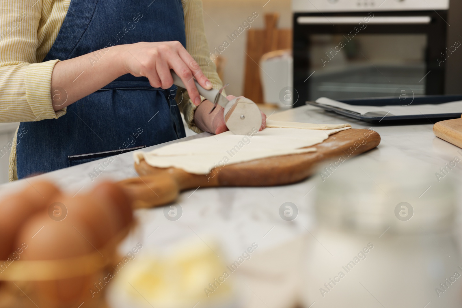 Woman cutting dough at light marble table indoors, closeup. Making croissants Photo of Woman cutting dough at light marble table indoors, closeup. Making croissants