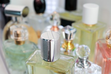 Photo of Different aromatic perfumes in bottles on shelf, closeup