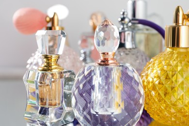 Photo of Different aromatic perfumes in bottles on light background, closeup