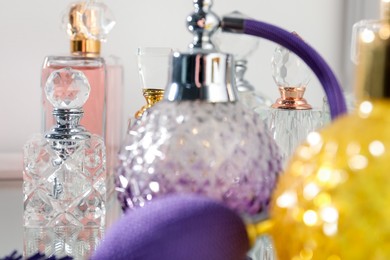 Photo of Different aromatic perfumes in bottles on mirror surface, closeup