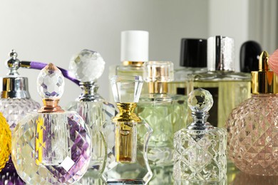 Photo of Different aromatic perfumes in bottles on mirror surface, closeup