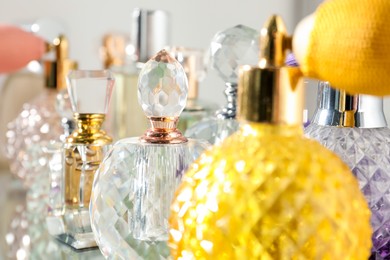 Photo of Different aromatic perfumes in bottles on light background, closeup