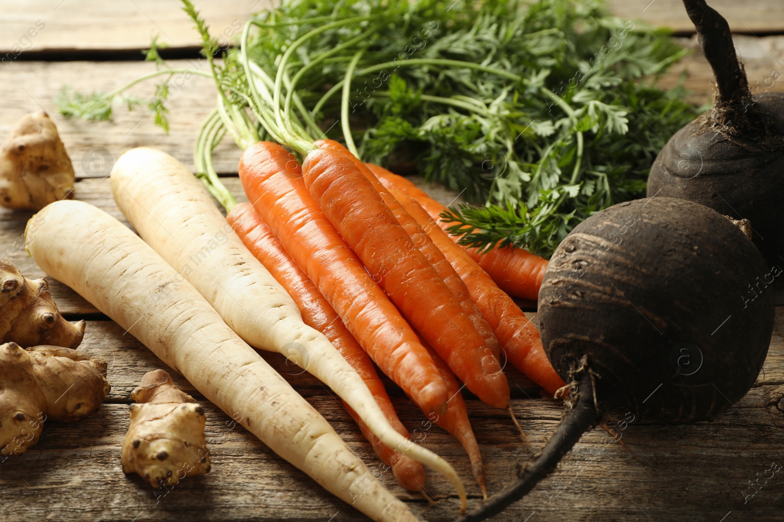 Photo of Different root vegetables on wooden table, closeup