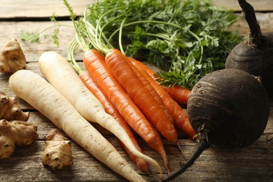 Photo of Different root vegetables on wooden table, closeup