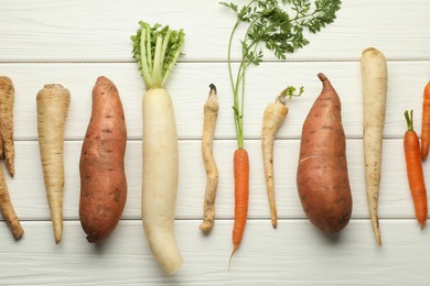 Photo of Different root vegetables on white wooden table, flat lay