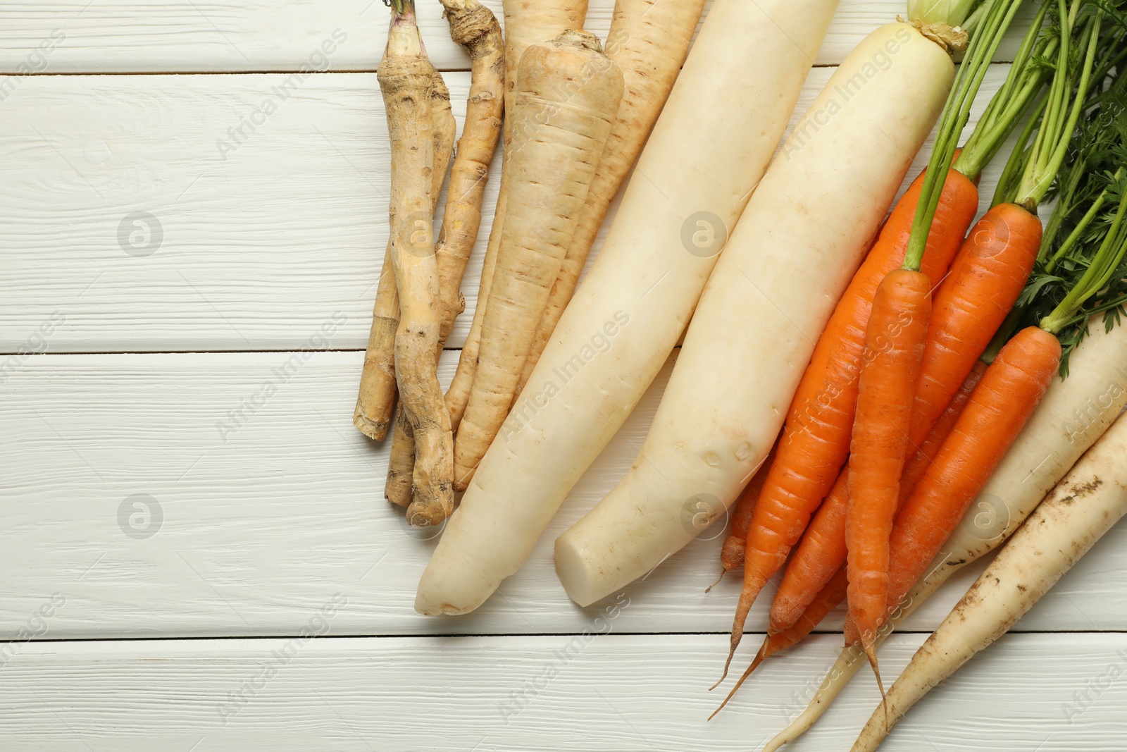 Photo of Different root vegetables on white wooden table, flat lay. Space for text