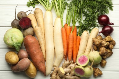 Different root vegetables on white wooden table, flat lay